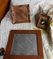 All three items arranged on surface: wood tray, reverse painting, framed tin panel