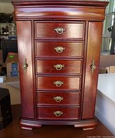 Front view of wood jewelry chest showing drawers and hardware, partial view of painted box