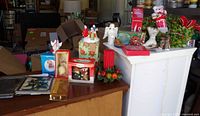 Countertop view showing porcelain angel, taper candles with fruit ring, boxed ornaments, assorted décor