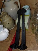 Two black wrought iron wall candle sconces on wooden surface