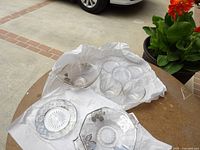 All glass pieces laid out on tissue showing three silver overlay dishes, three Candlewick coasters