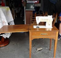 Sewing machine mounted in folding table, leaf extended