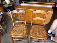 Front view of both wooden side chairs showing cane seats and different crest rails