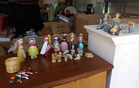 All groups displayed on table: spool dolls, Wade animals, wicker basket with tiny people, resin women in background