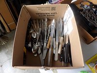 Cardboard box filled with assorted flatware and table knives