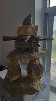 Photo of the resin Inukshuk sculpture placed indoors near a window showing stacked stone design and color tones.