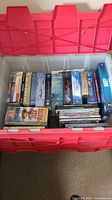 Photo showing a red storage container with multiple DVD box sets and cases inside, titles including nature documentaries, movies, and TV series.