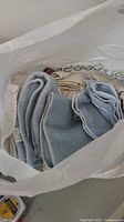 View of varied cleaning cloths and towels inside a white bag, assorted sizes and colors including blue, beige, and white.