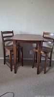 Front view of wooden counter height table with two chairs