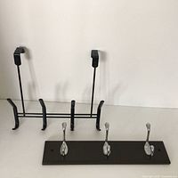 Black rectangular wall hook rack with three polished silver hooks mounted on black base.