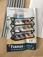 Front of packaging showing brand and product name with model shoe rack holding three rows of footwear.
