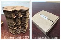 Photo of multiple stacks of unassembled flat die cut cardboard boxes in brown color.