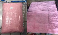 Light pink fluffy soft rug folded inside clear plastic packaging with a valve visible