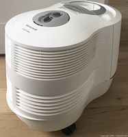 Front and side angle view of the white Honeywell humidifier showing the air vents, two control dials, and overall curved shape.
