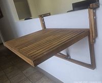 Wall-mounted foldable balcony table made of slatted acacia hardwood with espresso oiled finish, shown extended.