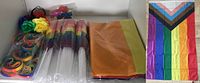 Photo showing mini flags, wristbands, rainbow feather accessories, and 5 large folded pride flags.