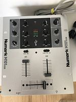 Top view of Numark M101USB mixer showing control knobs, sliders, and USB logo.