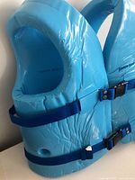 Side view of blue Super Soft PFD youth medium life jacket swim vest showing vinyl-coated foam and adjustable blue straps with Kwik-Snap buckles.