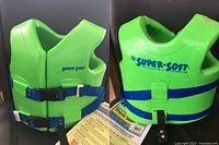 Front and back views of the bright green Super Soft brand vinyl-coated foam life jacket showing two blue adjustable straps with Kwik-Snap buckles and 'SUPER-SOFT' branding in blue.