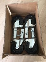 Four black rubber wheels swivel castors with metal mounting brackets in cardboard box.