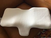 Angled view of the white ergonomic sleeping pillow with textured fabric cover and contoured design
