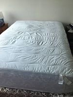 Full view of the white quilted mattress topper spread on a bed showing its size and fluffiness.