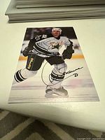 Front side of autographed hockey photo showing Guy Carbonneau in Dallas Stars jersey #21 with signature across player image.