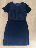 High end navy blue women’s dress laid flat, showing short sleeves, fitted waist, and glittery upper bodice detail.