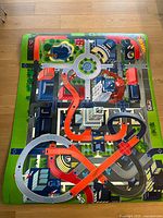Photo showing entire play mat with city road layout, multilevel tracks, buildings, and monster designs.