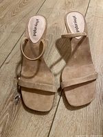 Top view of both sandals showing beige suede and dual strap design with Jeffrey Campbell branding on insoles.