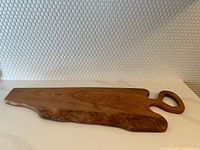 Full view of the mahogany charcuterie board showing the organic live edge and integrated handle.