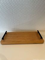 Solid wood rectangular tray with black metal handles on both sides, showing wood grain and finish