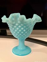 Front angled view of turquoise glass compote vase showing hobnail texture and ruffled rim.