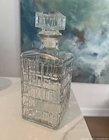 Front view of the vintage glass decanter showing clear glass with geometric grid cut design and matching stopper.