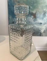 Front view of the vintage glass decanter showing diamond pattern and stopper on top.