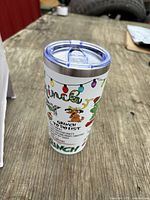 Side view of insulated stainless steel tumbler showing Grinch Christmas graphics and clear slide-closure lid