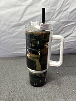 Side view of tumbler showing handle, lid, straw, printed exterior