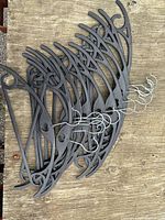 Stack of black plastic hangers with metal hooks on wood surface