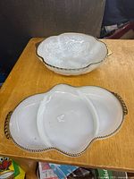 Top view of both milk glass serving pieces showing shapes, compartments and gold trim
