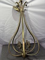 Side profile showing full teardrop frame, four candle sockets with bulbs, canopy and chain