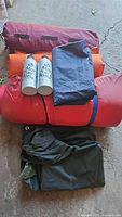 Stack of rolled sleeping bags and pads with two MSR fuel bottles on top