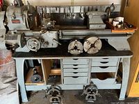 Overall view of Clausing lathe on stand with chucks, centers and rack of tooling