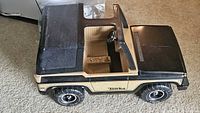 Side view of beige and black Tonka open-top SUV toy truck on carpet