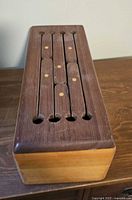 angled top view showing slotted dark wood lid with inlaid dots