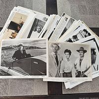 Stack of unsorted vintage publicity photographs on table