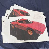 Stack of posters showing red Lancia Stratos artwork