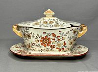 Side view of assembled tureen with lid and underplate showing floral pattern and handles