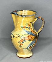 Left-side view showing full jug profile, handle, footed base, painted decoration