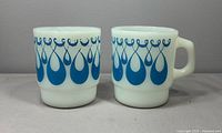 Front view of both white milk glass mugs showing blue swirl pattern