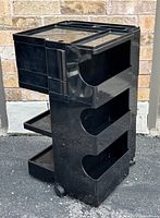 Front angled view showing three open side trays, top compartment, casters